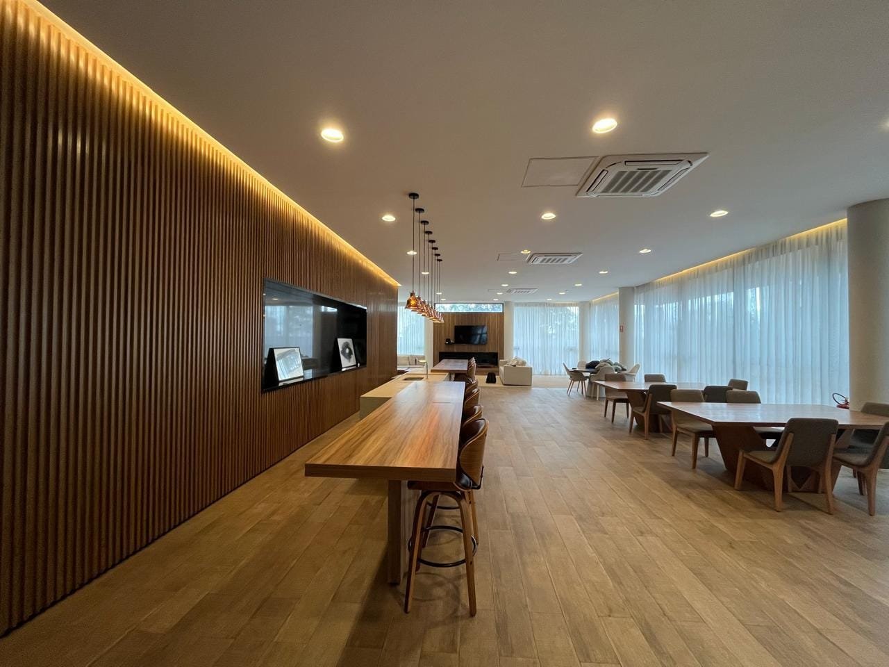 Salão de festas Sartoria Taquaral com bar em madeira ripada retroiluminado e TV