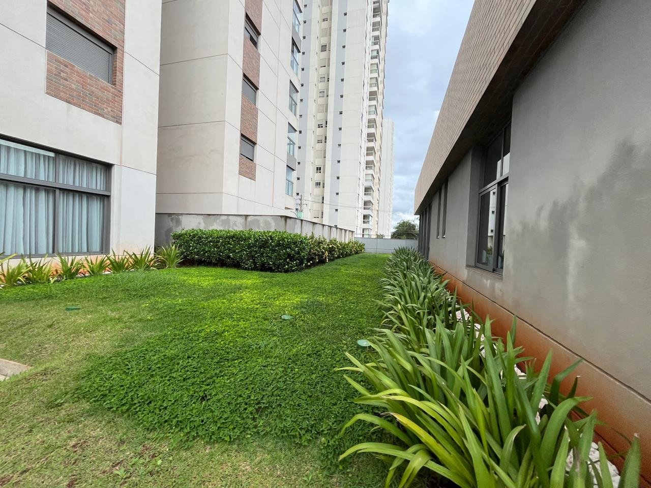 Jardim lateral verde com arbustos e gramado no Sartoria Taquaral