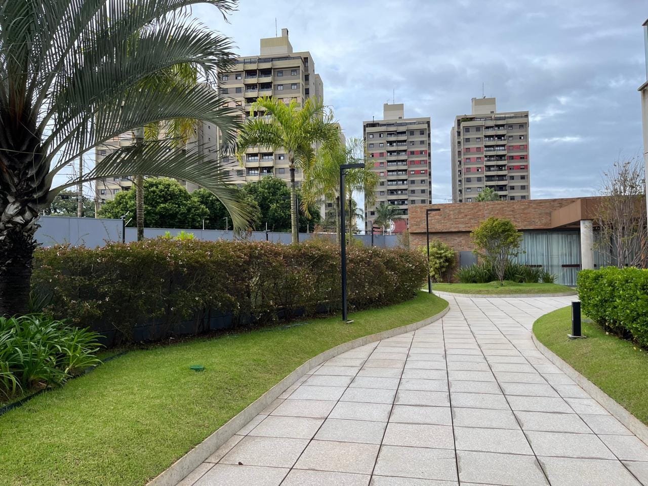 Caminho paisagístico entre jardins do Sartoria Taquaral com palmeiras e gramado