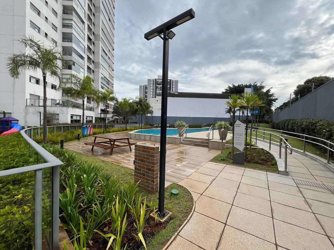 Vista panorâmica da área da piscina com torre e jardim no Sartoria Taquaral