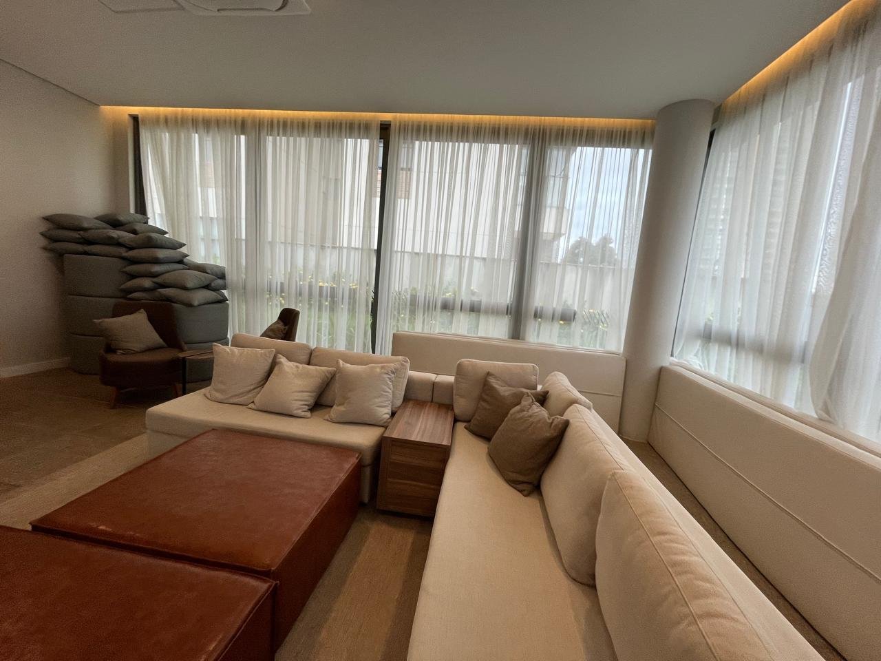 Lounge do salão de festas com sofás e janelões no Sartoria Taquaral