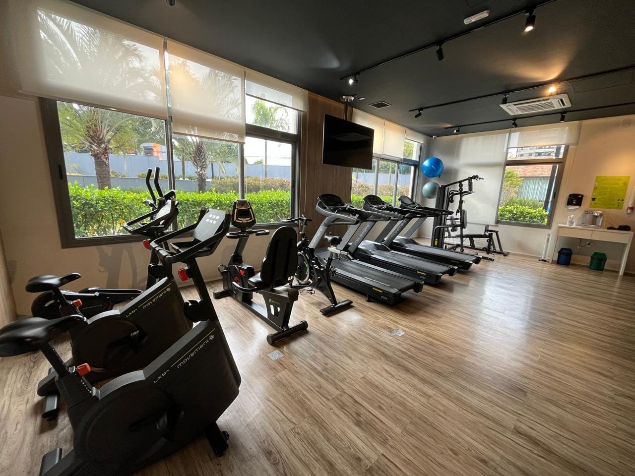 Academia Sartoria Taquaral com bikes, esteiras, TV e vista para o paisagismo