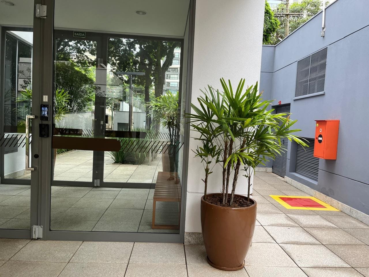 Jardim central interno do Sartoria Taquaral com árvore e bolards de iluminação