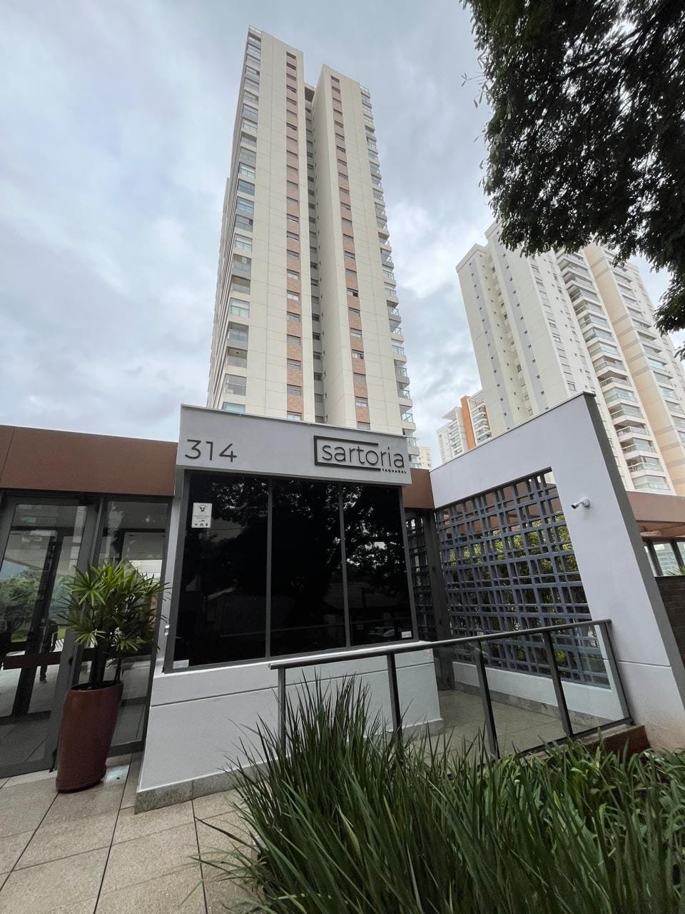 Portaria frontal do Sartoria Taquaral com jardim e placa do condomínio