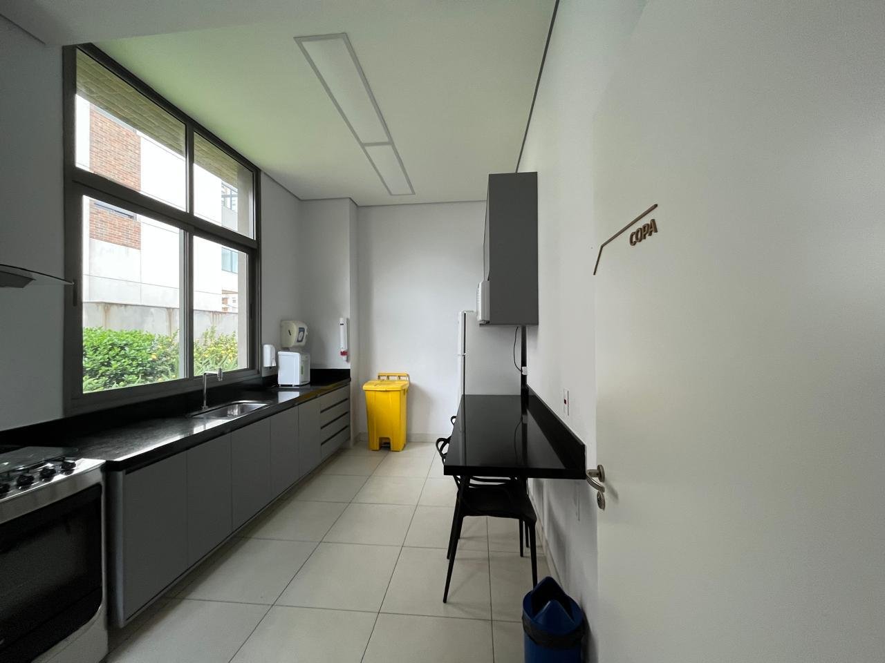 Lounge com sofá em L e parede ripada no salão Sartoria Taquaral