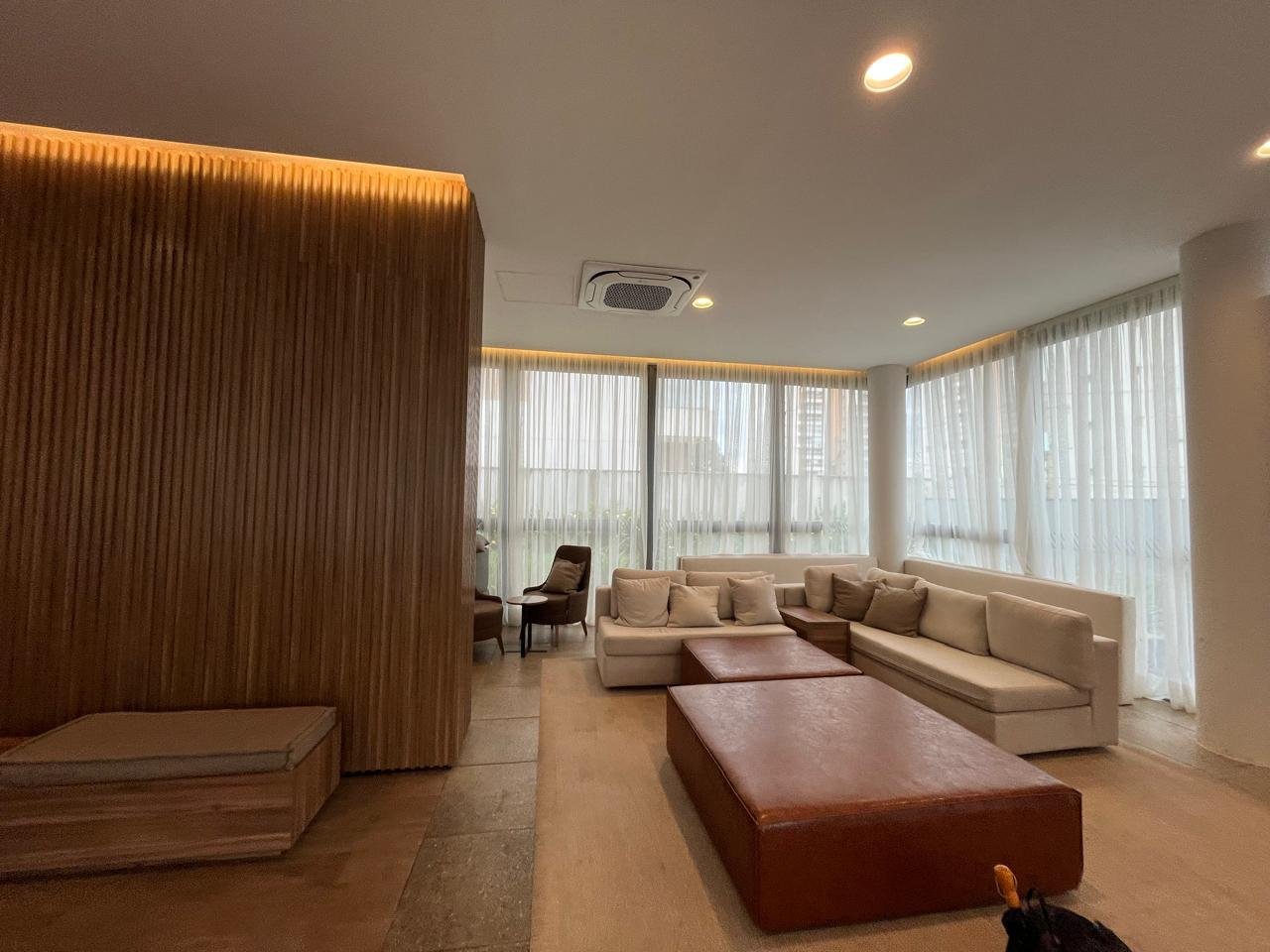 Detalhe do lounge com iluminação indireta e parede ripada no Sartoria Taquaral